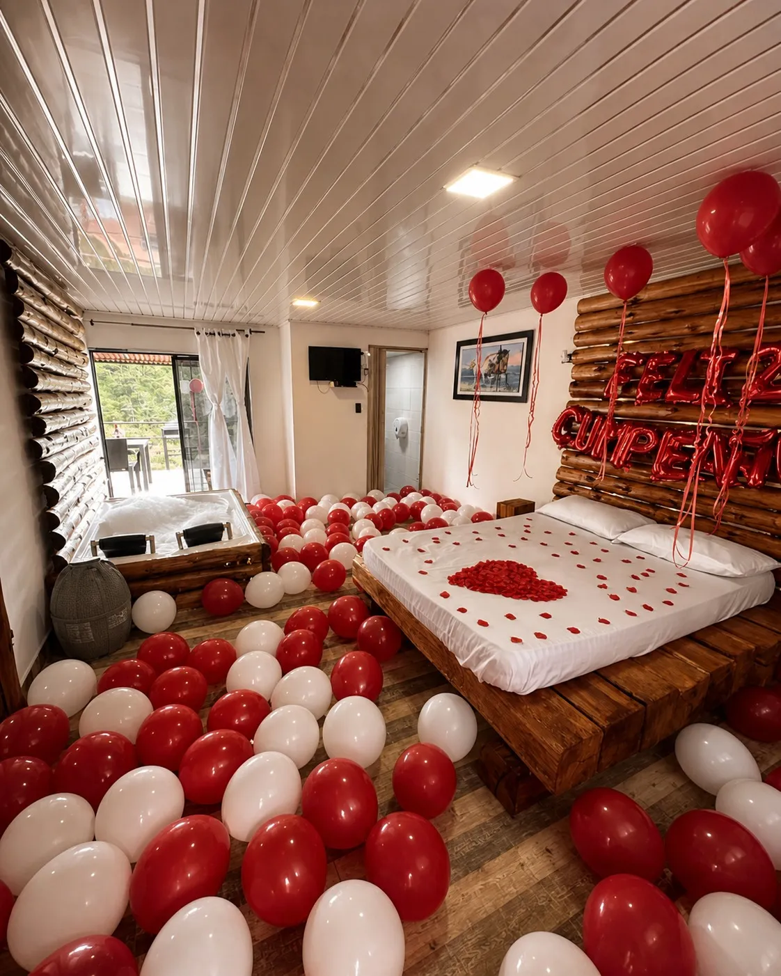 Habitación decorada con globos y un corazón sobre la cama para una sorpresa romántica